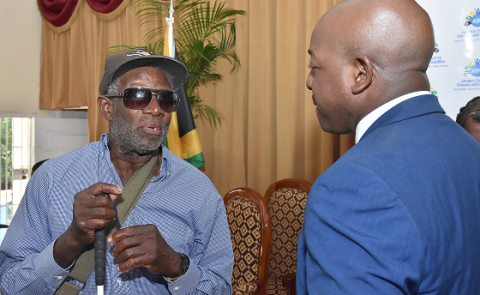 Minister Charles speaking with a visually impaired man